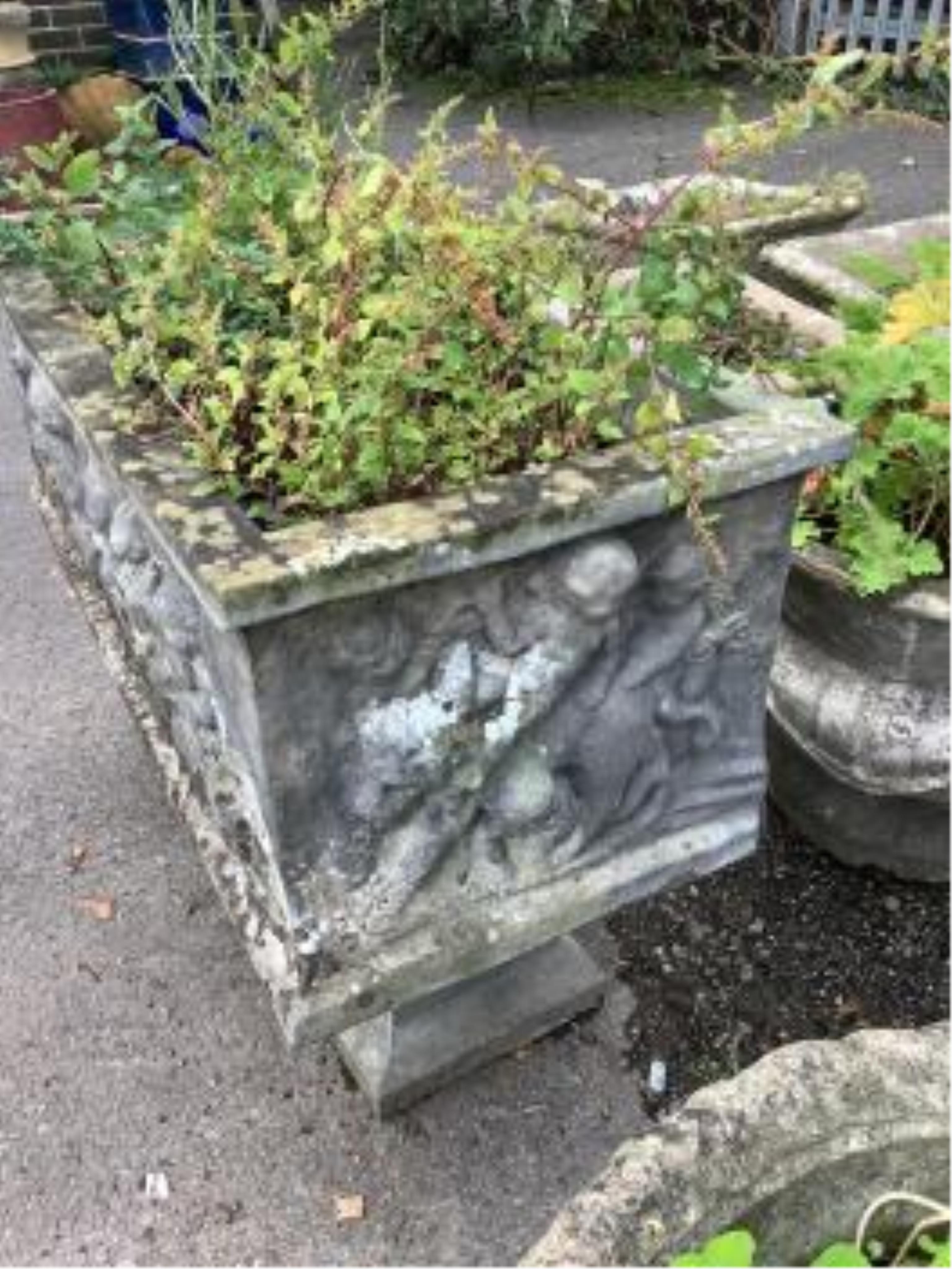 A reconstituted stone rectangular garden trough, moulded with putti, on Roman end plinths, width 89cm, depth 39cm, height 64cm. Condition - fair